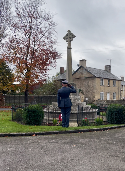 Squadron Leader Masters salutes after laying a wreath at the Brize Norton village memorial.